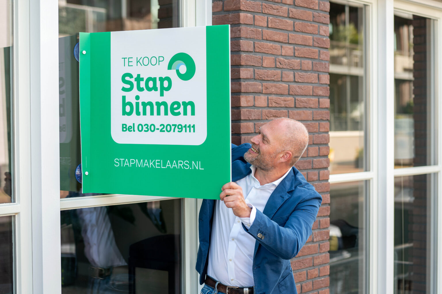 NVM Makelaar hangt te koop bord op in Utrecht